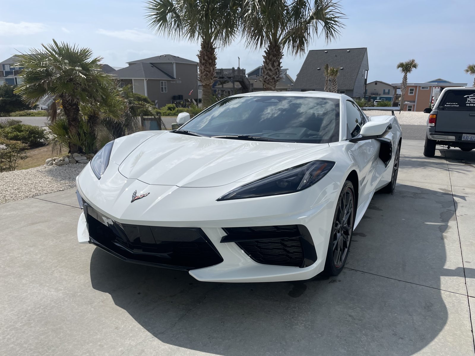 White Corvette C8 freshly detailed by Pittman Auto Detailing in an Oak Island driveway with palm trees